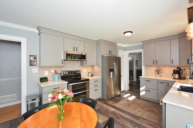 kitchen with tasteful backsplash, stainless steel appliances, dark hardwood / wood-style floors, and gray cabinetry