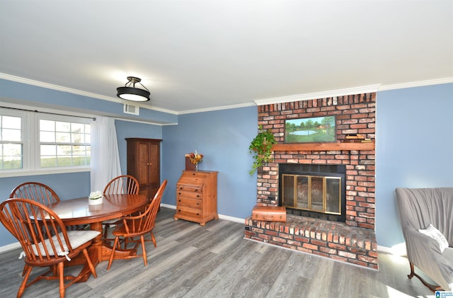 dining space with hardwood / wood-style floors, ornamental molding, and a fireplace