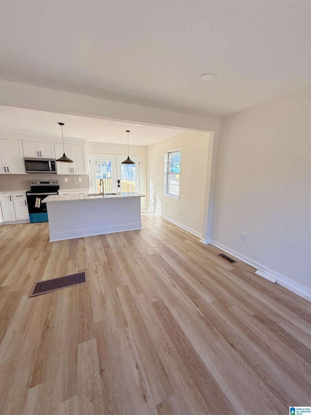 kitchen with a center island, white cabinets, hanging light fixtures, light hardwood / wood-style flooring, and appliances with stainless steel finishes