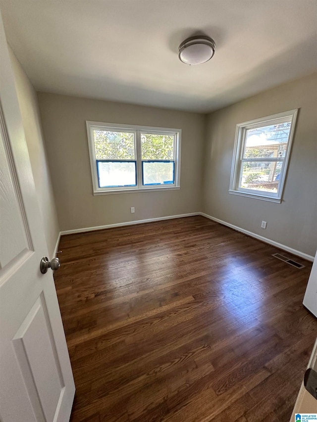 empty room featuring dark hardwood / wood-style flooring and a wealth of natural light