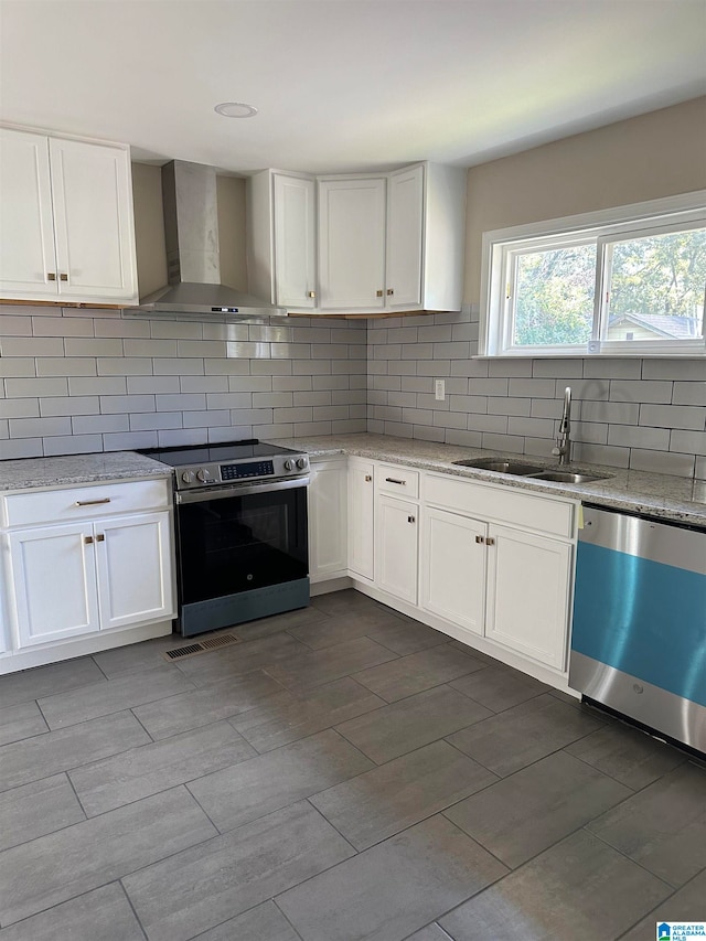 kitchen with sink, white cabinets, wall chimney range hood, and appliances with stainless steel finishes