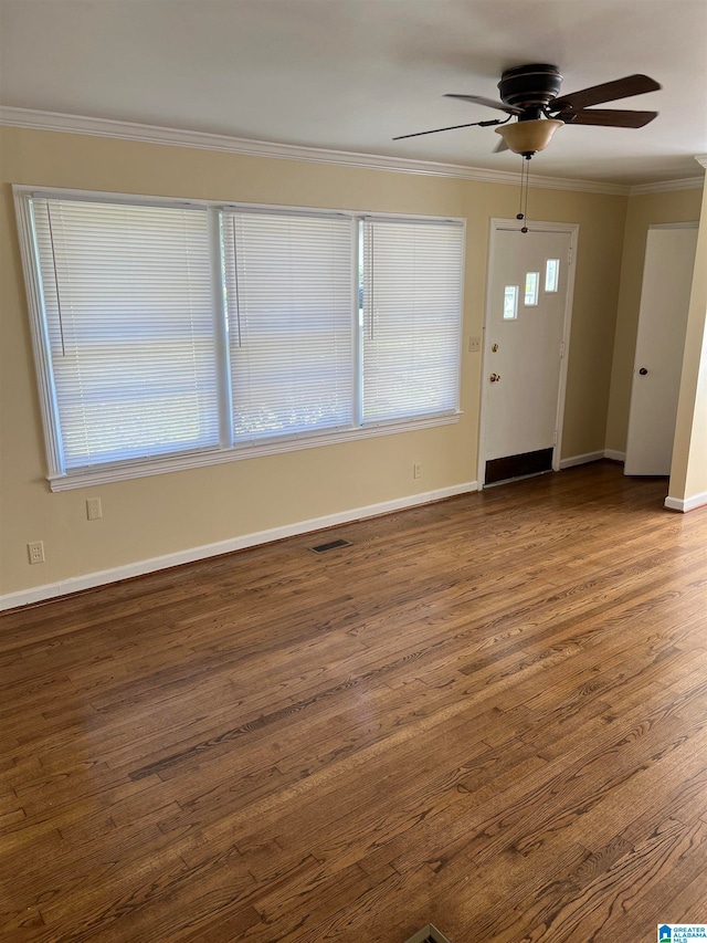 interior space featuring ceiling fan, plenty of natural light, dark wood-type flooring, and ornamental molding