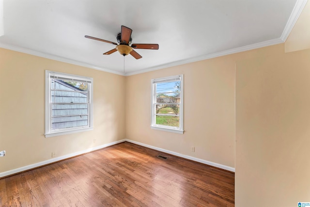 empty room with hardwood / wood-style floors, a wealth of natural light, ornamental molding, and ceiling fan