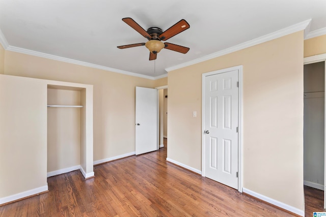 unfurnished bedroom with two closets, ceiling fan, crown molding, and dark hardwood / wood-style floors