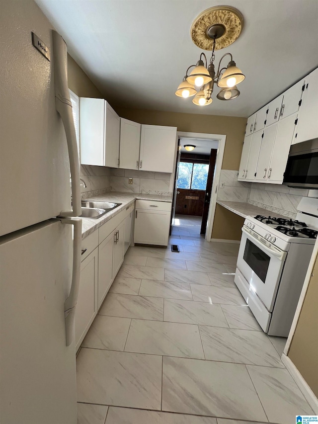 kitchen featuring decorative backsplash, white cabinetry, white appliances, and an inviting chandelier