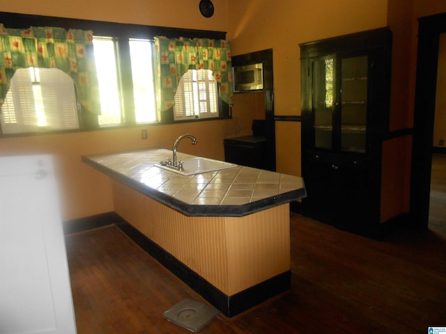 kitchen with kitchen peninsula, tile countertops, dark hardwood / wood-style floors, and sink