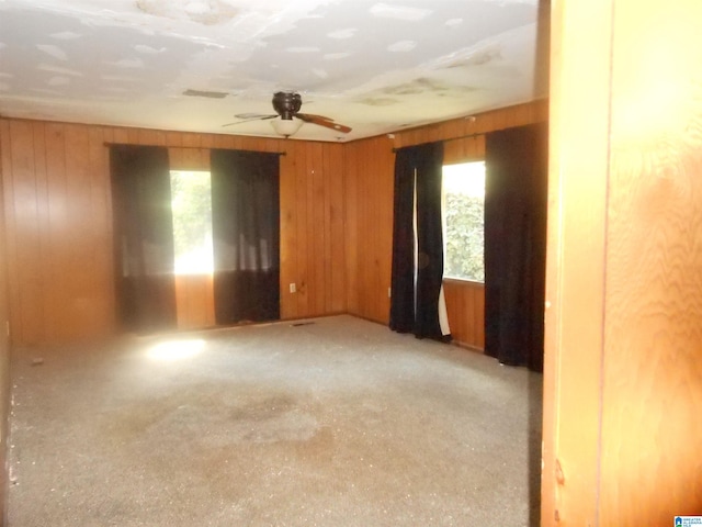 spare room featuring ceiling fan and wooden walls