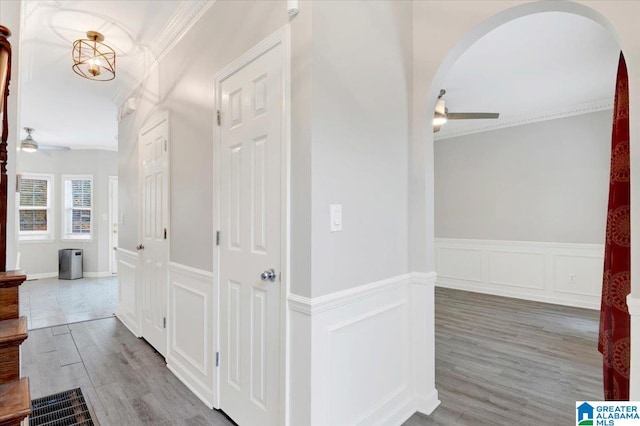 corridor with an inviting chandelier, ornamental molding, and hardwood / wood-style flooring