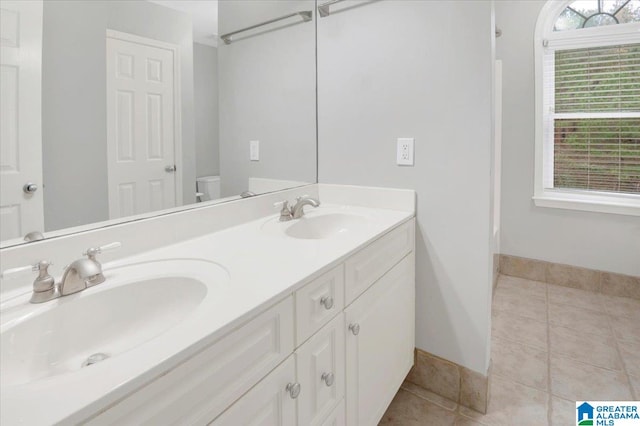 bathroom with tile patterned floors, vanity, toilet, and a wealth of natural light