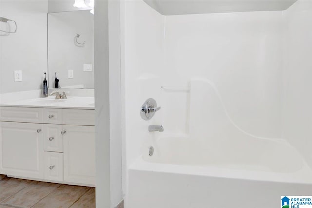 bathroom with hardwood / wood-style floors, vanity, and washtub / shower combination