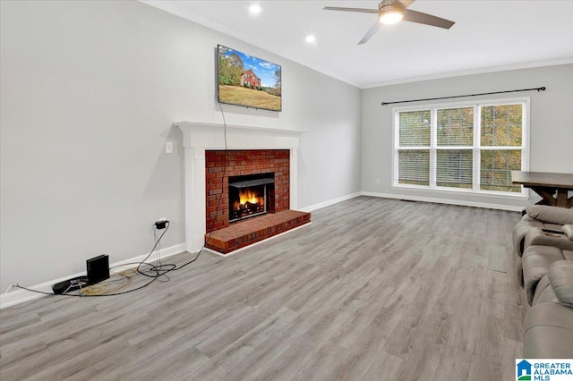 unfurnished living room featuring a fireplace, light hardwood / wood-style floors, ceiling fan, and crown molding