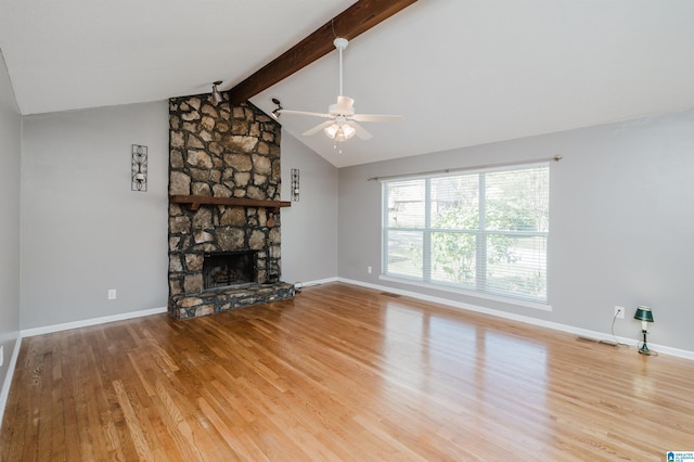 unfurnished living room with wood-type flooring, lofted ceiling with beams, a stone fireplace, and ceiling fan