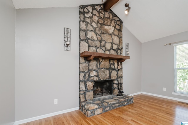 unfurnished living room with a fireplace, lofted ceiling with beams, and hardwood / wood-style flooring