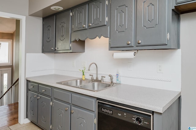 kitchen featuring gray cabinetry, dishwasher, backsplash, and sink