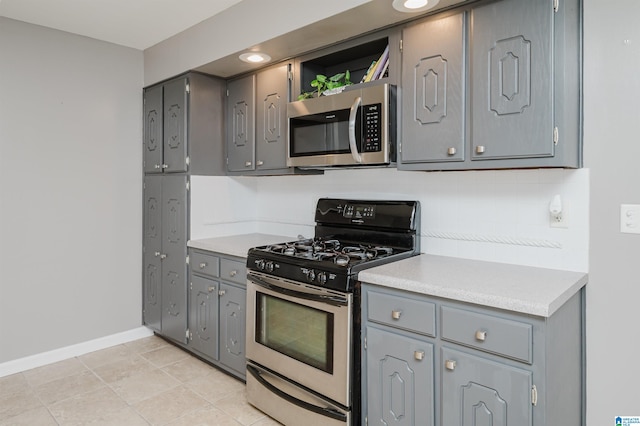 kitchen featuring gray cabinetry, light tile patterned floors, and appliances with stainless steel finishes