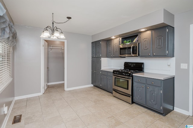 kitchen with a chandelier, decorative light fixtures, gray cabinets, light tile patterned floors, and appliances with stainless steel finishes