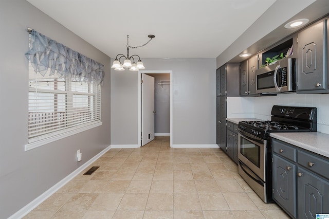 kitchen with light tile patterned floors, stainless steel appliances, hanging light fixtures, and a chandelier