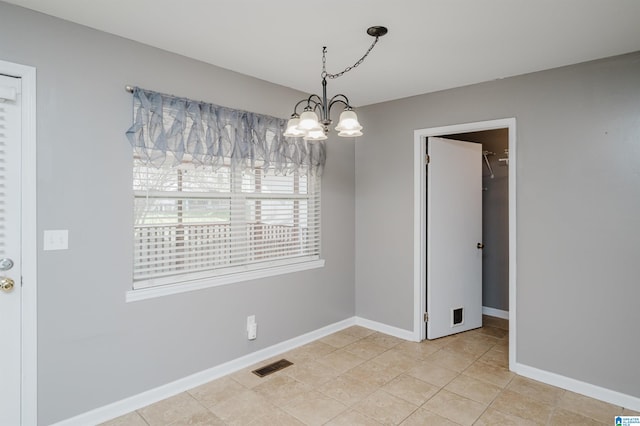 tiled empty room featuring an inviting chandelier