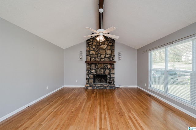 unfurnished living room featuring a wealth of natural light, a fireplace, wood-type flooring, and vaulted ceiling