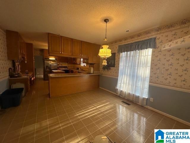 kitchen with tile patterned flooring, hanging light fixtures, kitchen peninsula, and a textured ceiling