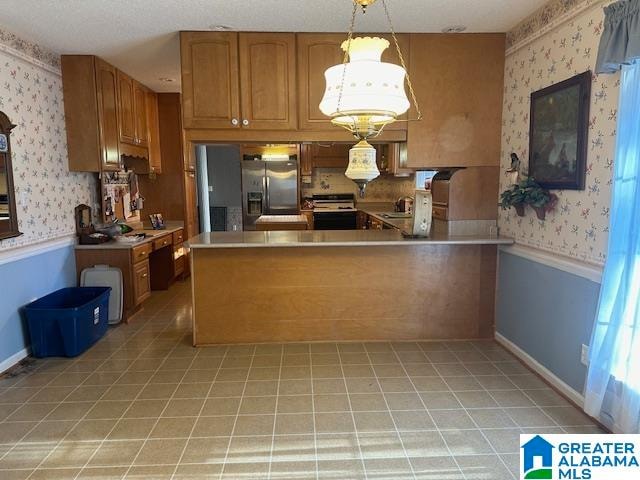 kitchen featuring decorative light fixtures, stainless steel refrigerator with ice dispenser, kitchen peninsula, sink, and range with electric stovetop