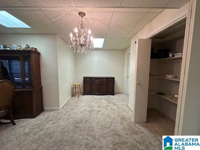 interior space with a drop ceiling, carpet, and a notable chandelier