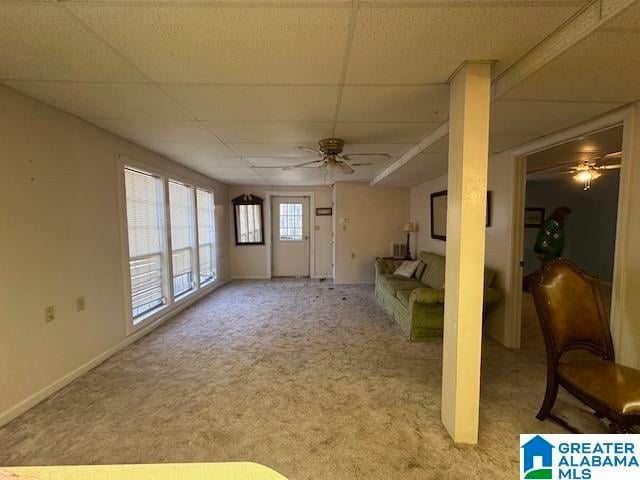 unfurnished living room with ceiling fan, a drop ceiling, and light carpet