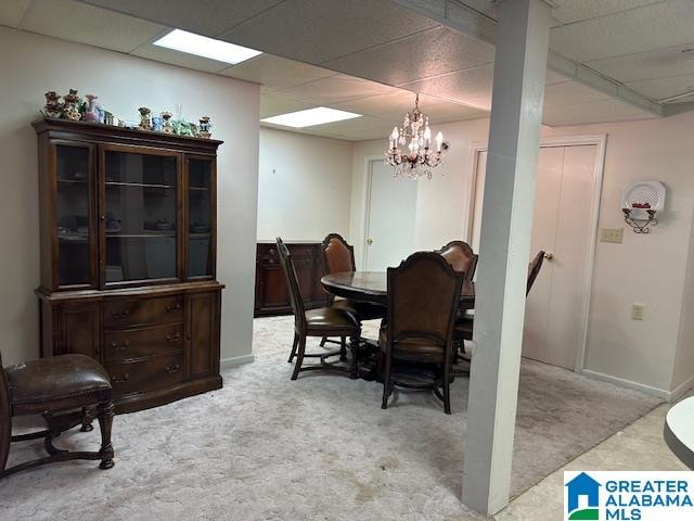 dining room featuring light carpet, a paneled ceiling, and a chandelier