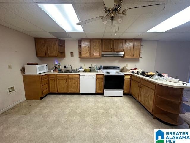 kitchen with white appliances, sink, kitchen peninsula, ceiling fan, and a drop ceiling