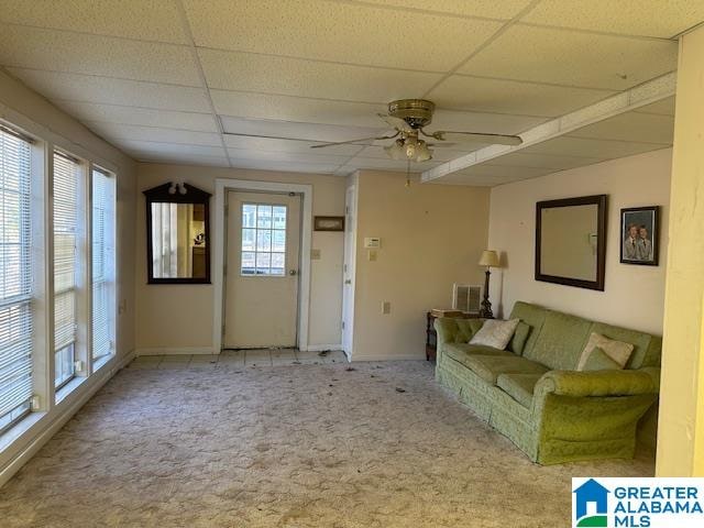 unfurnished living room with ceiling fan, light colored carpet, a paneled ceiling, and a healthy amount of sunlight