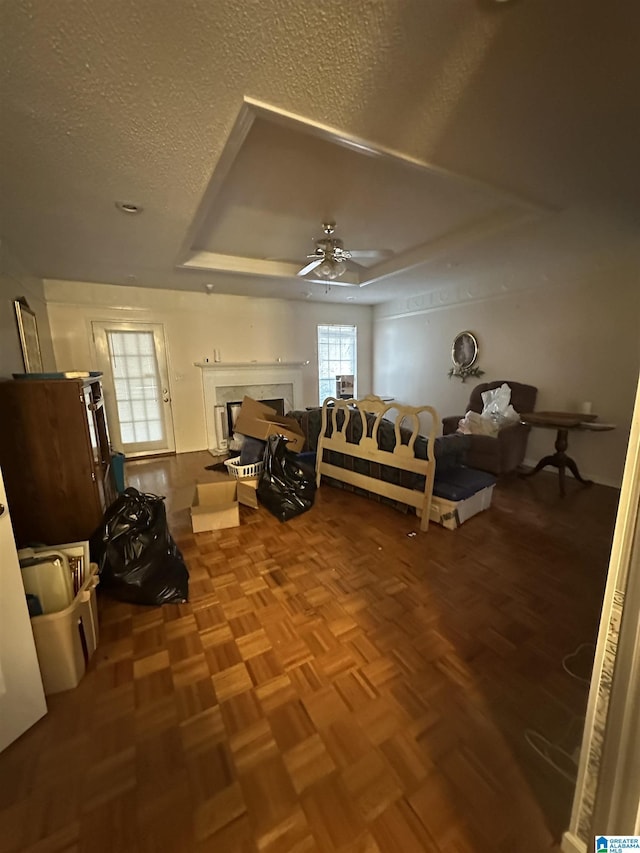 bedroom with ceiling fan, parquet flooring, a textured ceiling, and a fireplace