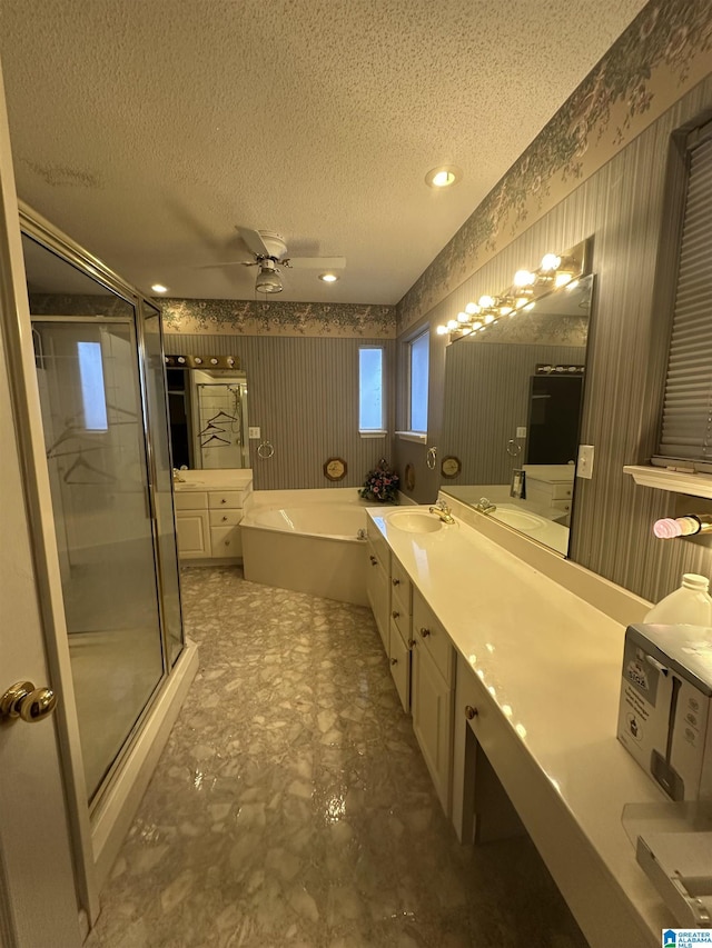 bathroom with a textured ceiling, independent shower and bath, vanity, and ceiling fan