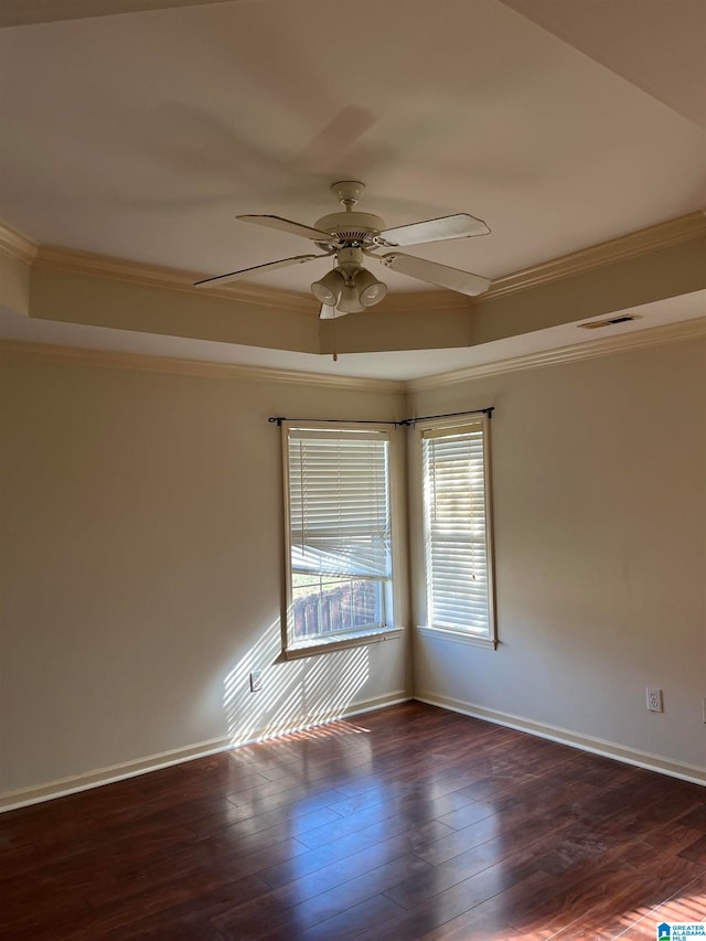 empty room with dark wood-type flooring, a raised ceiling, and ceiling fan