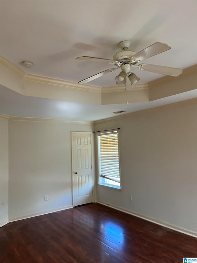 spare room with ceiling fan, dark hardwood / wood-style floors, a tray ceiling, and ornamental molding