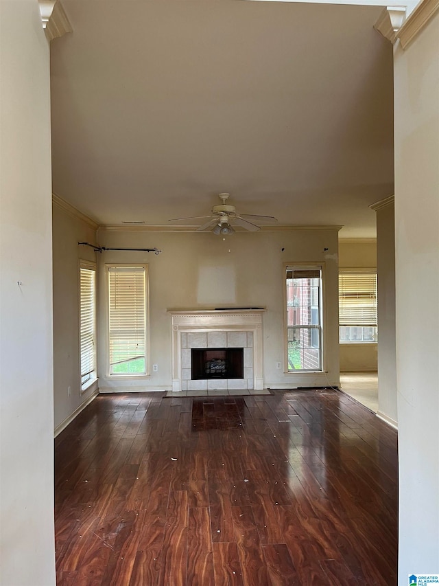 unfurnished living room with ceiling fan, a tiled fireplace, ornamental molding, and hardwood / wood-style flooring