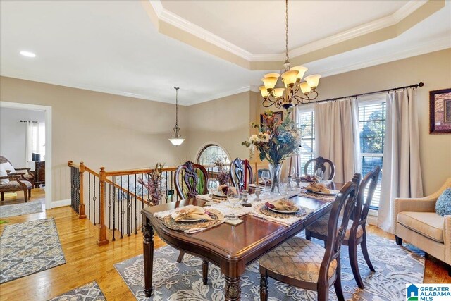 dining room featuring a tray ceiling, light hardwood / wood-style flooring, and ornamental molding