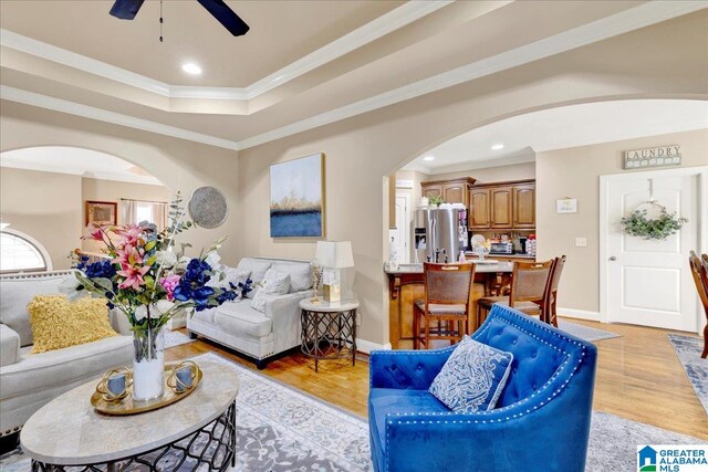 living room featuring ceiling fan, ornamental molding, and light hardwood / wood-style flooring