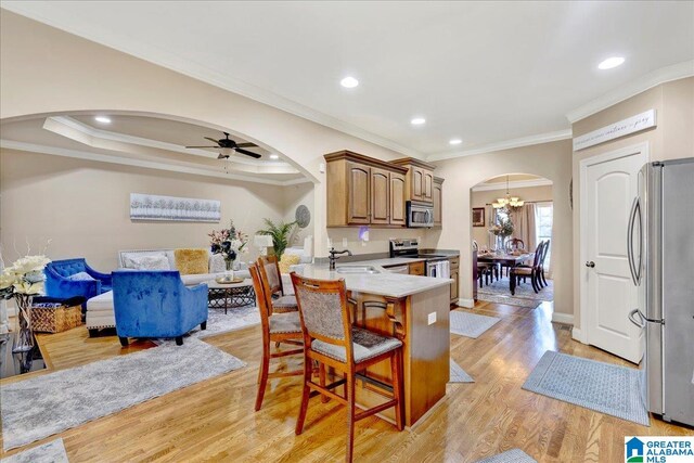 kitchen featuring a kitchen bar, kitchen peninsula, stainless steel appliances, sink, and light hardwood / wood-style flooring