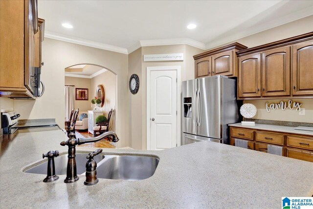 kitchen with stainless steel fridge, sink, crown molding, and range