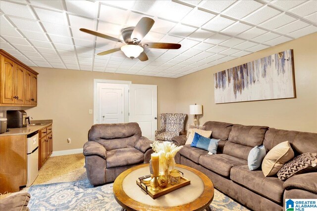 carpeted living room with ceiling fan and sink