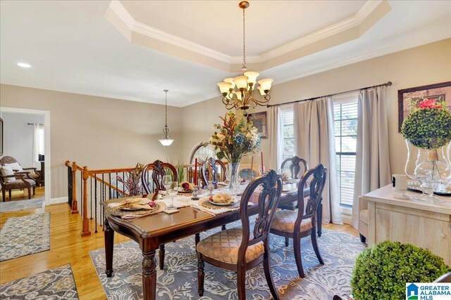 dining space featuring a raised ceiling, light wood-type flooring, and crown molding