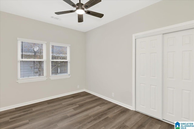 unfurnished bedroom with dark wood-type flooring, ceiling fan, and a closet