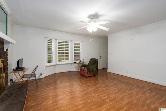 living area with hardwood / wood-style flooring, a brick fireplace, and crown molding