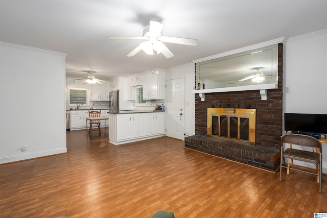 living room featuring crown molding, hardwood / wood-style floors, sink, and a brick fireplace