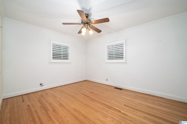 empty room with a textured ceiling, light wood-type flooring, and crown molding