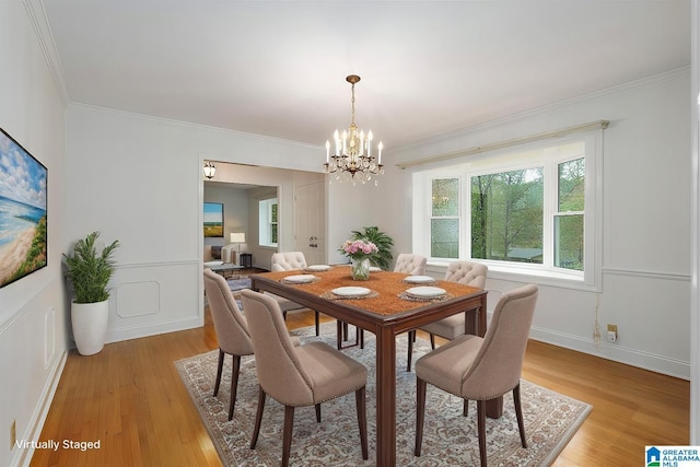 dining area featuring ornamental molding, light wood-style floors, and a decorative wall