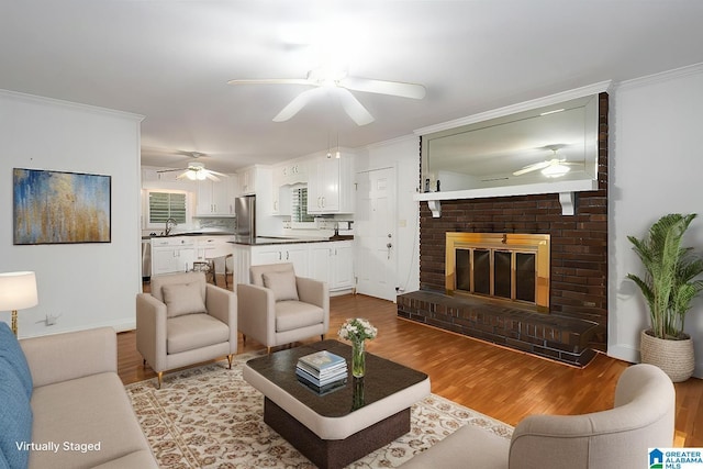 living area with ornamental molding, light wood-type flooring, and ceiling fan