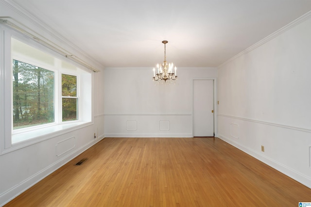 spare room featuring light hardwood / wood-style flooring, an inviting chandelier, and ornamental molding