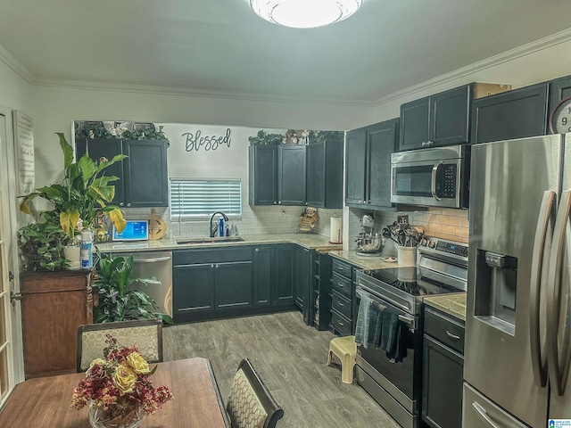 kitchen with crown molding, light countertops, light wood-style flooring, stainless steel appliances, and a sink