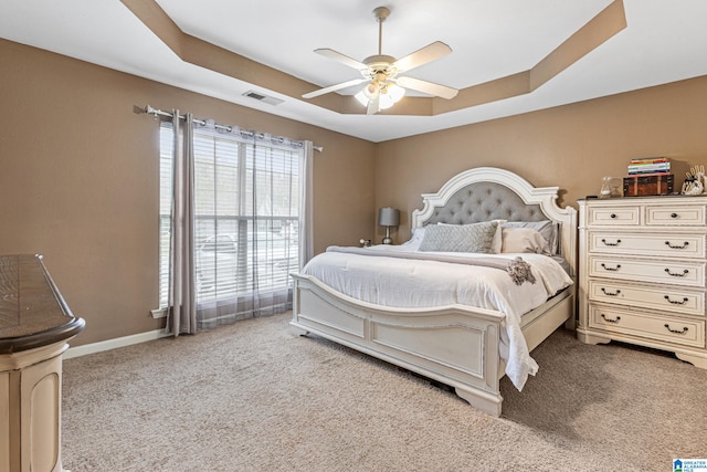 carpeted bedroom with a tray ceiling and ceiling fan